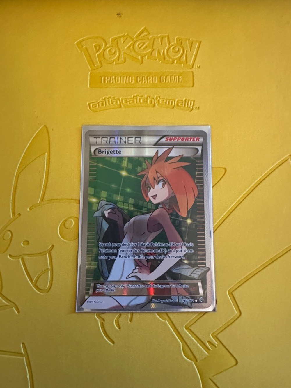 Pokémon Trainer Card - Brigette (Holo) on Yellow Pikachu Playmat